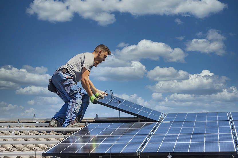Technicien posant un panneau photovoltaïque sur les rails d'une toiture